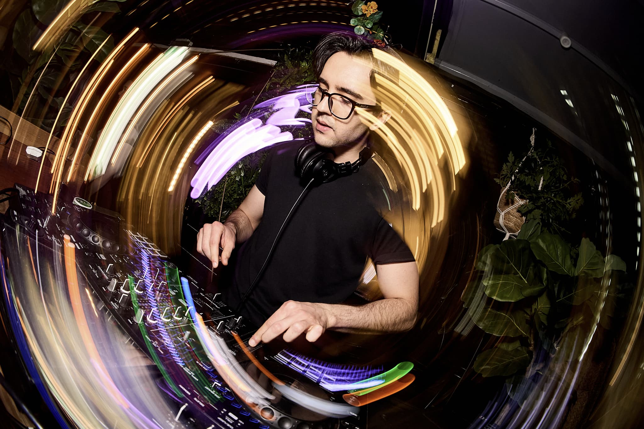DJ at the decks wearing a cap and headphones