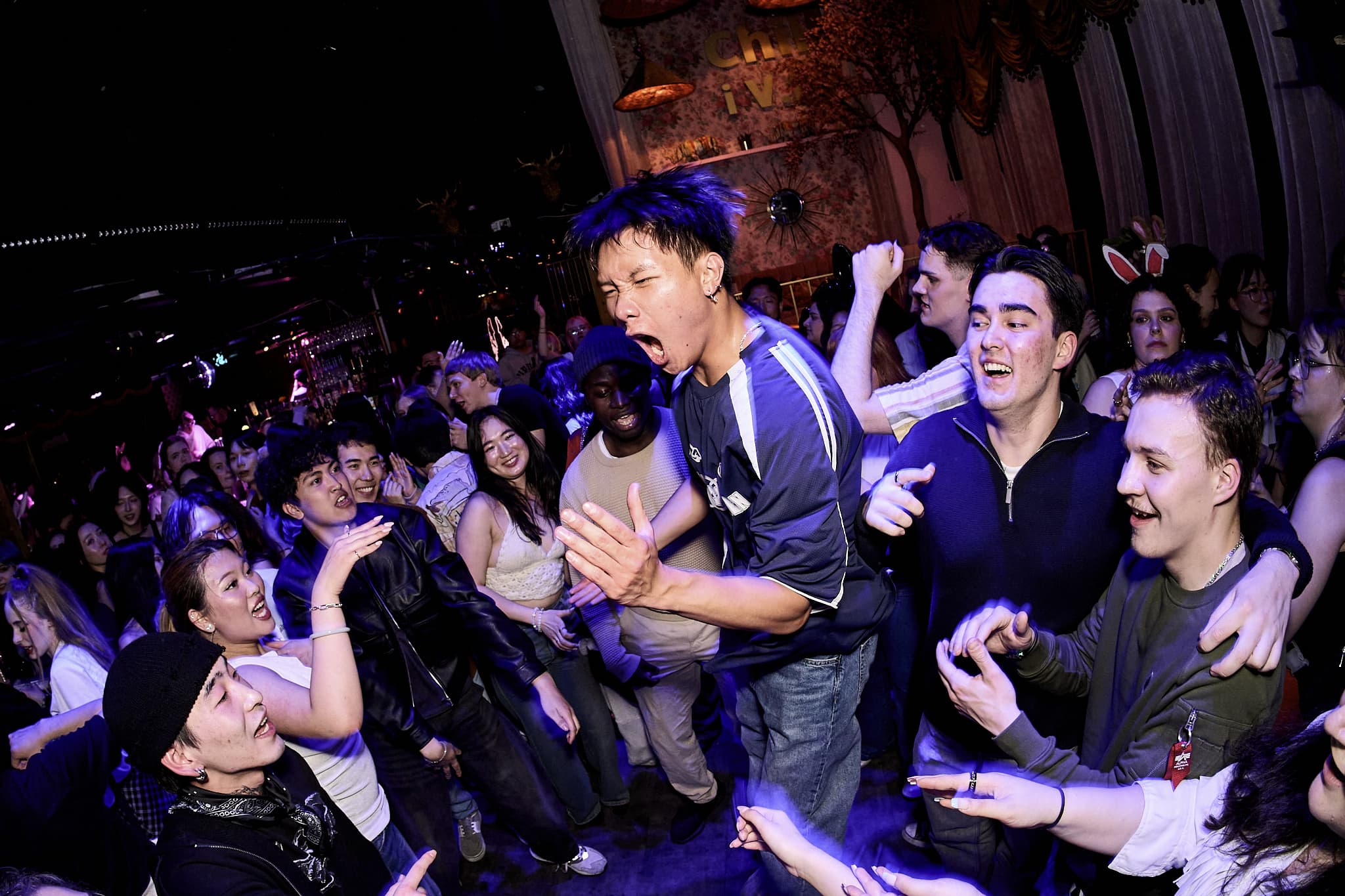 Pink and blue laser beams above a crowded dance floor